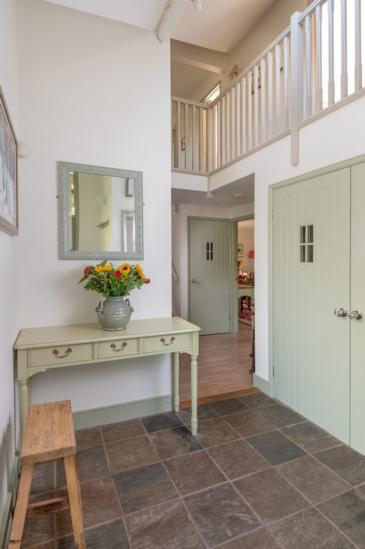 View of entrance hall with mirror, flowers, place to sit, calm colours