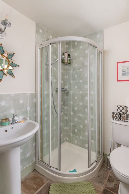 Downstairs shower with patterned tiles, star-shaped mirror and fuchsia-coloured picture frame