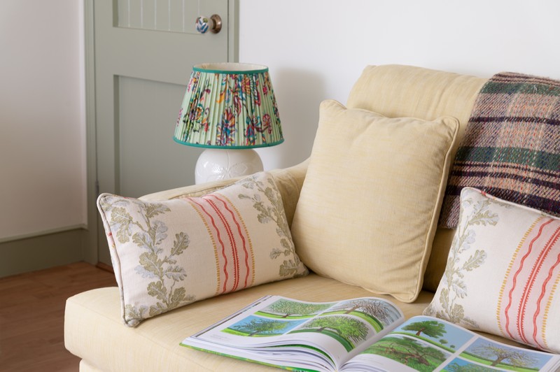 Decorative door handle, Matthew Williamson lamp and Linwood fabric cushions and recycled wool blanket on sofa in drawing room