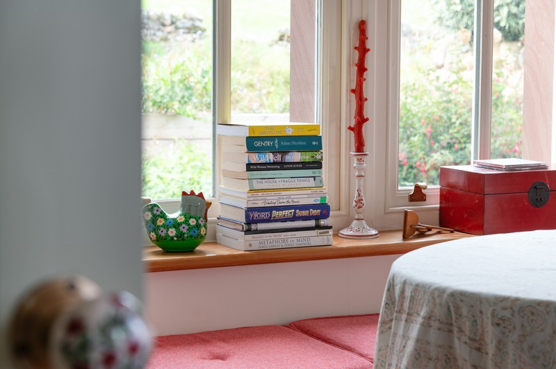 View of bay window in drawing room, with decorative candles, books and table