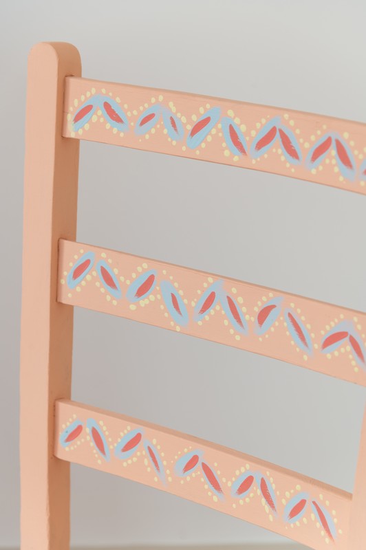 Detail of hand painted coral, blue, pink and yellow chair in second bedroom