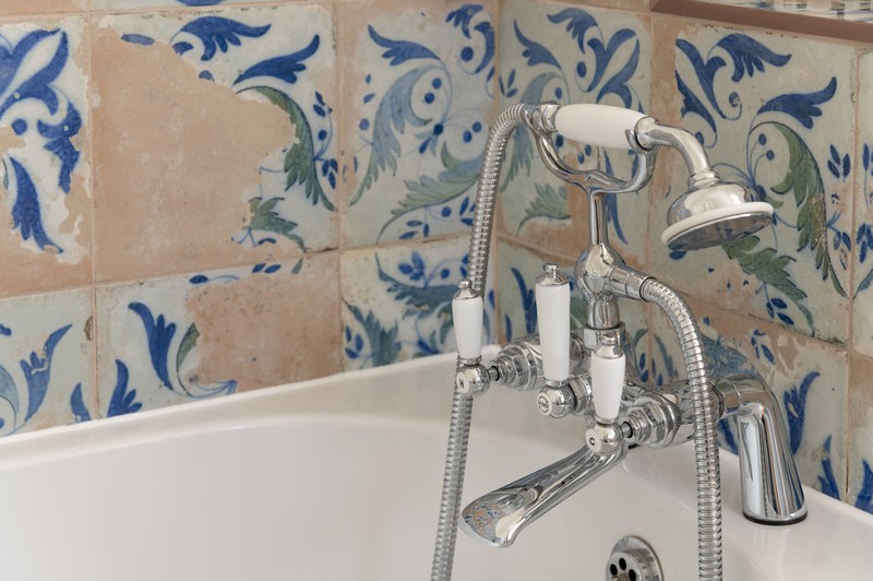 Mediterranean-inspired shabby chic bathroom tiles and shower/bath tap in upstairs bathroom with more of bath